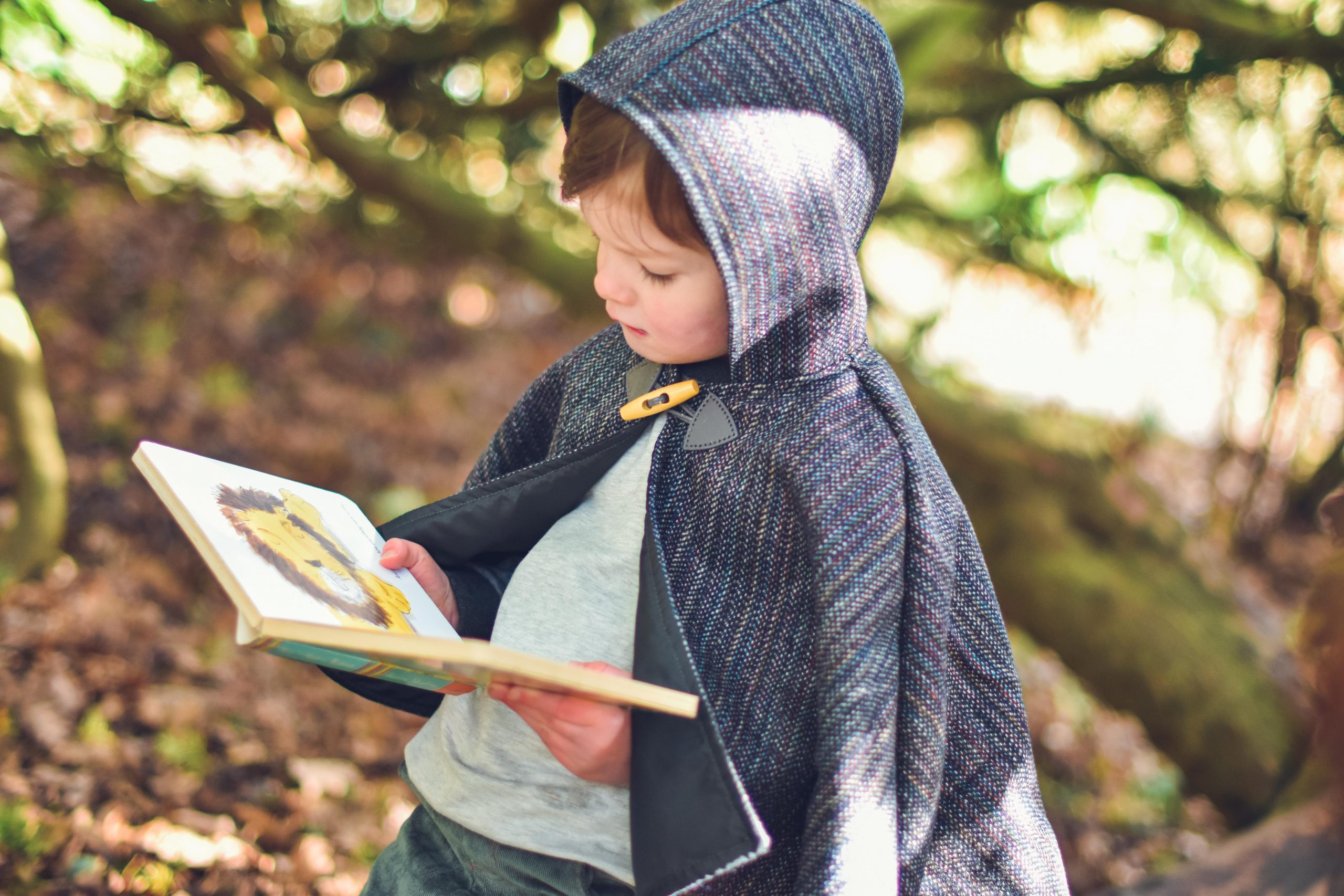 Waves and Wild Storybook Cape boy wearing grey cape reading book
